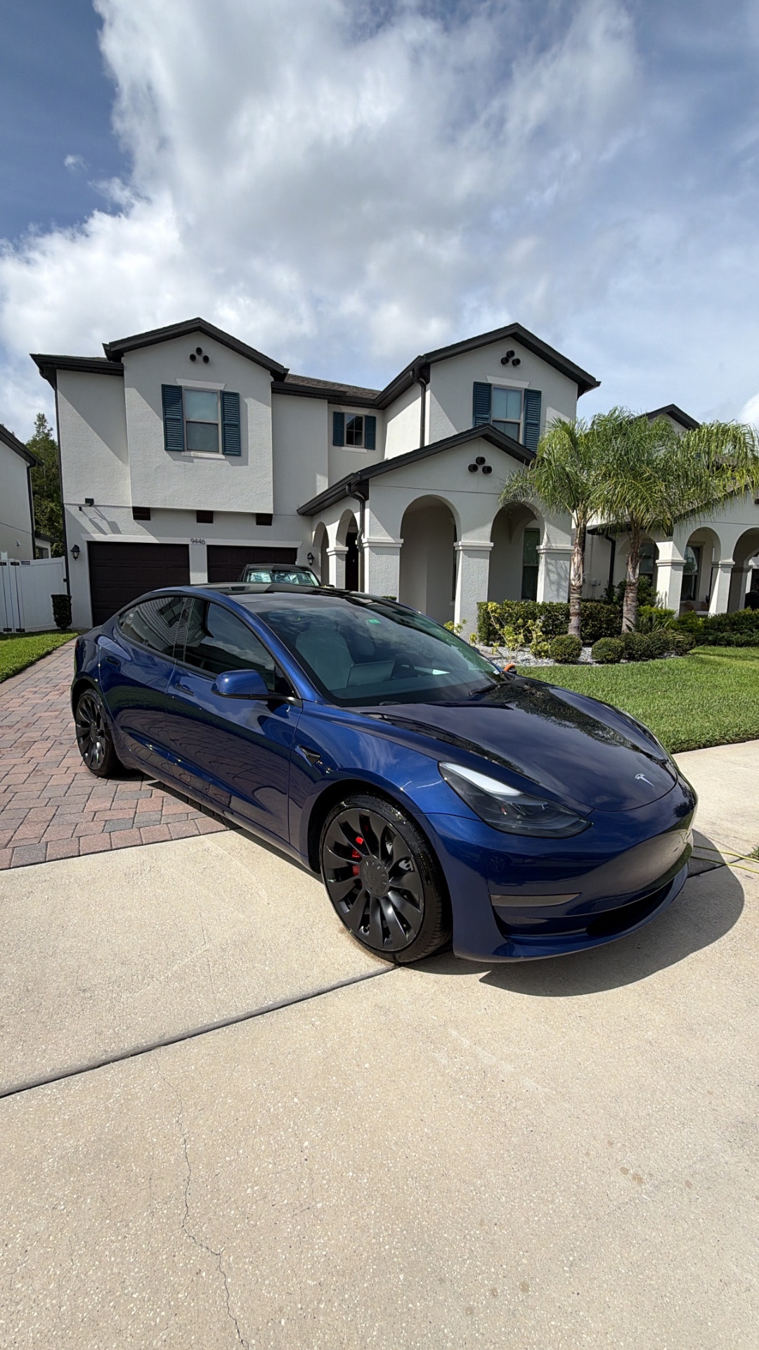 Glossy blue Tesla freshly detailed in a Florida driveway